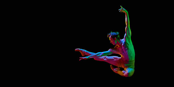 istock Banner with one young man, ballet dancer jumping in air over dark studio background with neon light. Copy space for ad, text. Freedom 1485133419