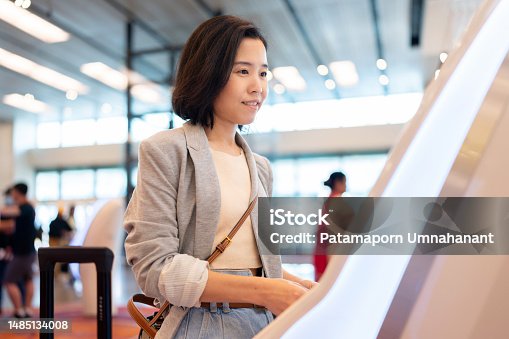 istock Technology facilitates fast and still has high security. Asia travel woman use kiosk automatic check in machine to check in online and get boarding pass. Scanning passport to record the passenger information in the system. 1485134008