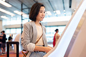 Technology facilitates fast and still has high security. Asia travel woman use kiosk automatic check in machine to check in online and get boarding pass. Scanning passport to record the passenger information in the system.