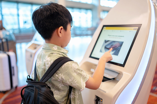 Information security can use technology to control and store systematically. Asia boy check in at automatic check in kiosk. Touching screen and choose flight detail and insert passport to record data in system to create boarding pass.