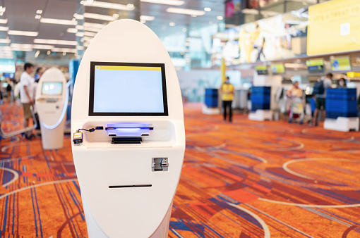 Unrecognizable people at the airport. Automatic check in machine located at the airport are provided to facilitate passengers in check-in.