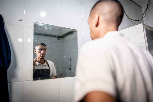 Young man looking at a screaming reflection of himself in a mirror