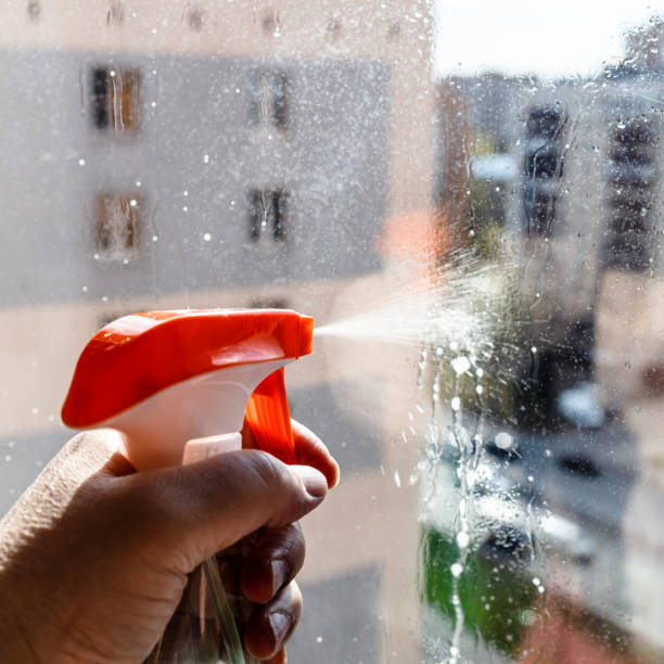 istock hand sprays washing liquid on window glass closeup 1485137687