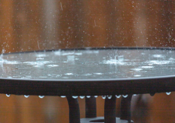 Heavy rain splashing onto outdoor glass table. Heavy rain background. Rain storm concept.