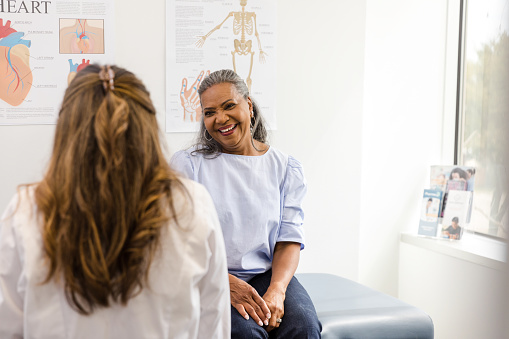 Mujer adulta mayor activa sonríe mientras habla con el médico photo