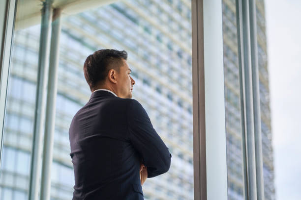istock asian businessman standing by window looking at view 1485138784