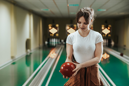 Shot of a cute young woman holding bowling ball at the bowling club.
