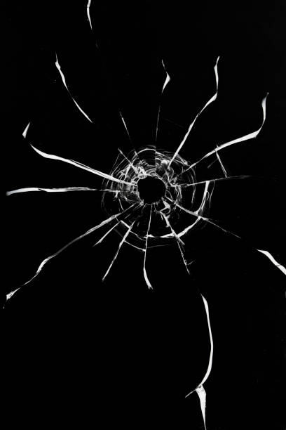 istock Broken glass shot, crack texture with bullet hole on black background. 1485142880