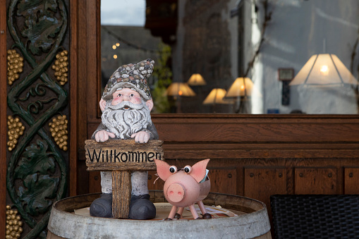 Carved wooden gnome and a wooden pig standing on a barrel outside a souvenir and gift shop in Germany