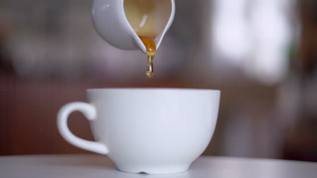 Pouring Honey Into White Coffee Cup Slow Motion