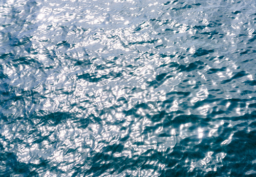 Diffused daylight making gentle reflections on the rippled waves of a water surface.