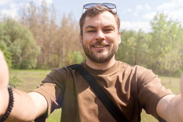 istock Man takes a selfie outdoors in the park using his mobile phone. 1485150315