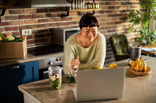 Close up of a Young Japanese food nutritionist talking to her clients over a video call