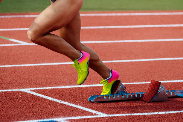 close-up legs female runner start running from starting blocks on red track stadium, summer athletics championships