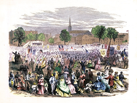 Vintage illustration depicts a festive scene in Washington, D.C., as African Americans celebrate the abolition of slavery in the District of Columbia on April 19, 1866. The image shows a large group of people gathered together, dressed in their finest clothes and holding banners and signs commemorating the occasion.