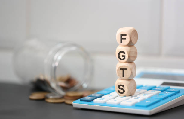 the acronym fgts written on wooden dice lying on top of a calculator. a glass jar and brazilian decoins in the composition. - retirement investment capital letter text imagens e fotografias de stock