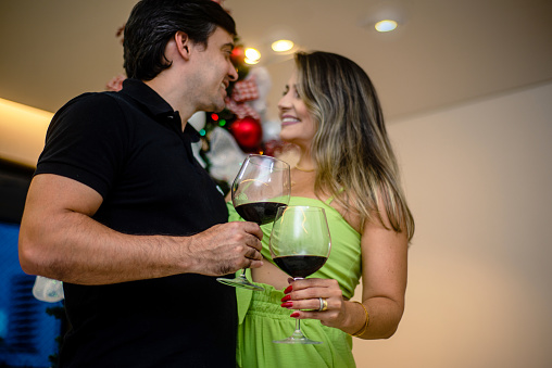 Couple celebrating on Christmas night. Wine glasses. Kiss.