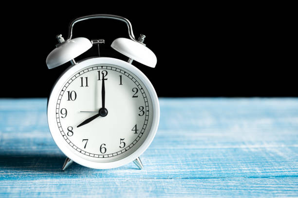 istock Close-up, a white Alarm clock shows 8 am on a blurred dark background. 1485163716