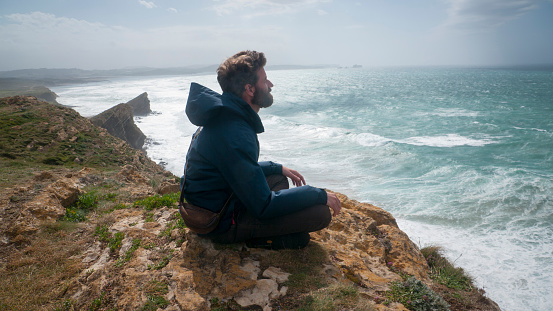 Man sitting in a cliff by the sea horizon