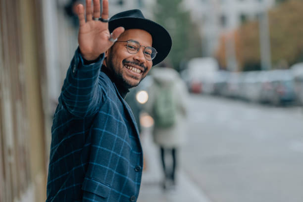 istock young man waving smiling on the street 1485165253
