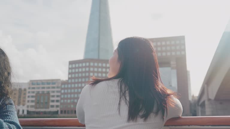 Rear view of Asian woman tourist sightseeing along the River Thames on boat tours in London, United Kingdom