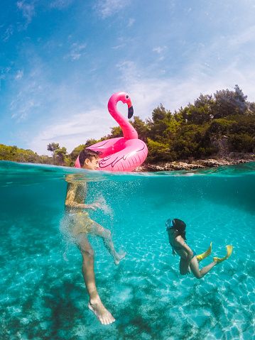 Young girl in snorkeling mask dive underwater with tropical fishes in coral reef sea pool. Travel lifestyle, water sports, outdoor adventure, swimming lessons on family summer beach holiday with kid