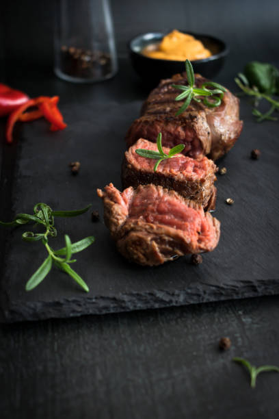 istock Grilled beef steak with balsamic and rosemary on a stone table. On a black background 1485172477