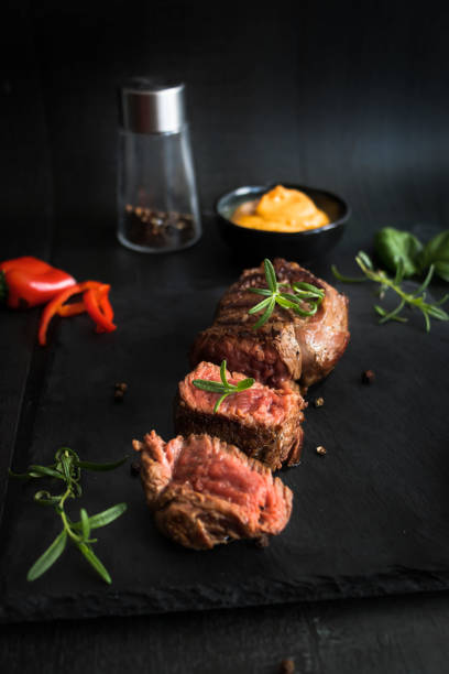 istock Grilled beef steak with balsamic and rosemary on a stone table. On a black background 1485172483