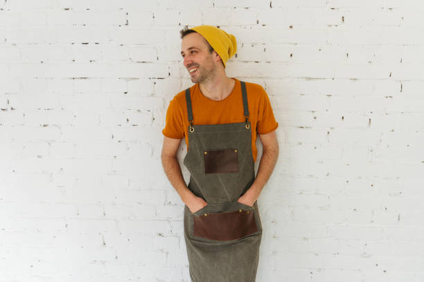 Portrait of a young male chef wearing an apron, on a white background.