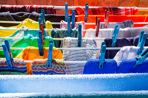 Multi-colored clothes hang attached to clothespins and dry after washing, close-up.