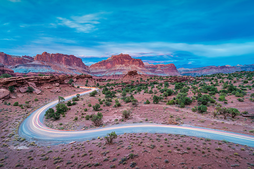 Long exposure of cars driving on a winding dirt road in Capitol Reef National Park Utah USA at Sunset Point.