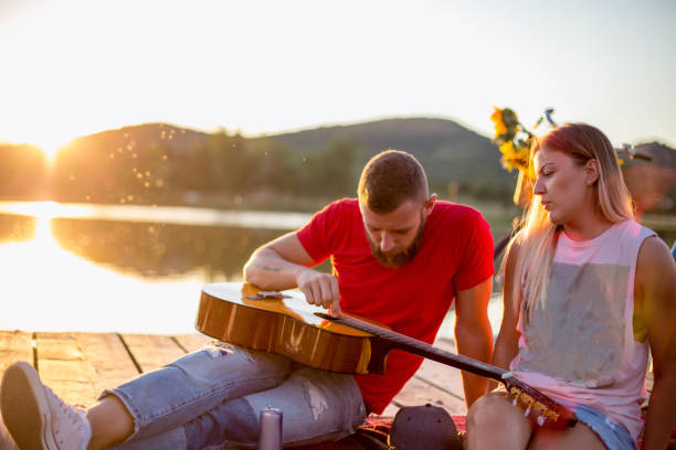 istock Young couple sitting on lake pier enjoying sunset 1485181520