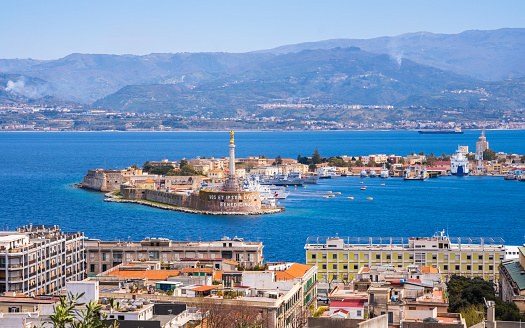 The Strait of Messina between Sicily and Italy. View from Messina town with golden statue of Madonna della Lettera and entrance to harbour. Calabria coastline in background.
