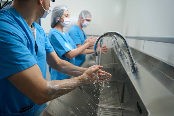 hombres y mujeres se lavan bien las manos antes de la operación - scrubbing up fotografías e imágenes de stock