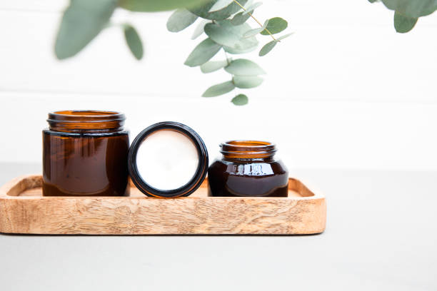 Amber bottles with facial mask and cream with a branch of eucalyptus on the gray concrete background stock photo