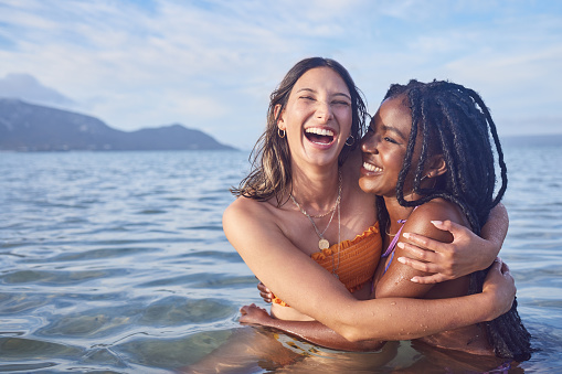 Funny, ocean and happy with friends swimming at beach for relax, summer break and vacation with blue sky mockup. Travel, bonding and diversity with women for peace, nature and tropical holiday