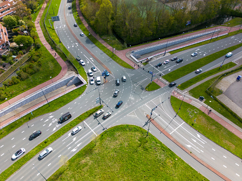 This aerial drone picture shows a road crossing from above. There is some traffic driving on the road.