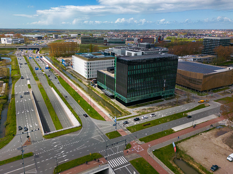 This picture is made with a drone. It shows several office buildings next to a large road and traffic junction in Leiden. Leiden is a beautiful city in the province of zuid-holland.