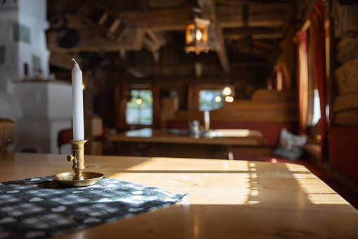 Candle on the table. illuminated by sunlight, in the interior of an alpine restaurant, Austria. High quality photo