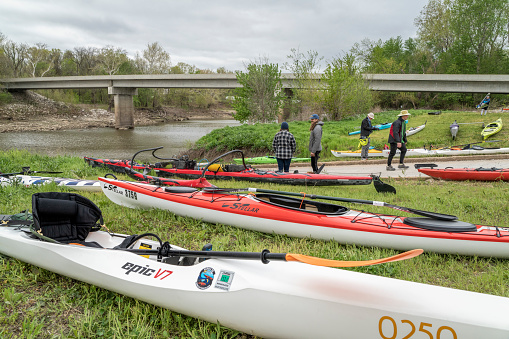 Lamine, MO, USA - April 22, 2023: Paddlers and boats (kayaks, outrigger canoe, surfski) on a shore of the Lamine River in spring scenery.
