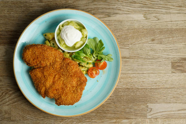 istock Schnitzel, Fried Chicken with Cucumber salad and vegetables 1485210386