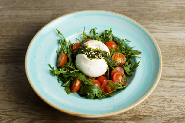 salada de burrata caprese com rúcula, pesto e tomate em um prato sobre uma mesa de madeira - vinegar salad dressing balsamic vinegar cooking oil - fotografias e filmes do acervo