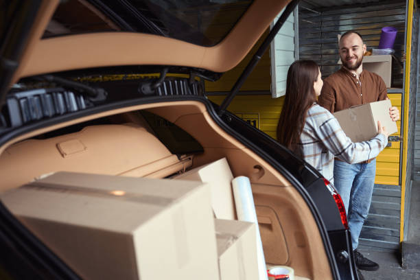 istock Two joyful people holding a box by the car 1485212037