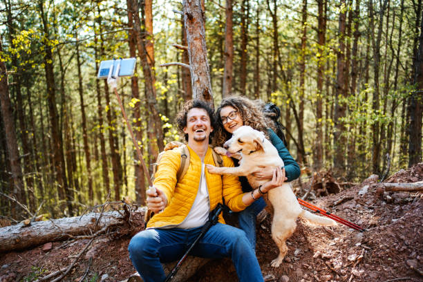 istock Young couple with white dog taking selfies with a selfie stick while on a break from hiking 1485212618