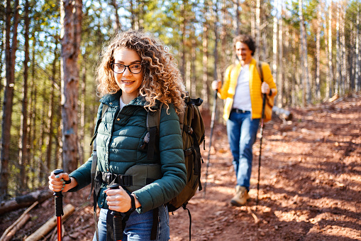 Portrait of a young woman with eyeglasses and curly hair while hiking in the forest