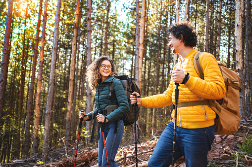Young adventurous couple with backpacks hiking in the forest
