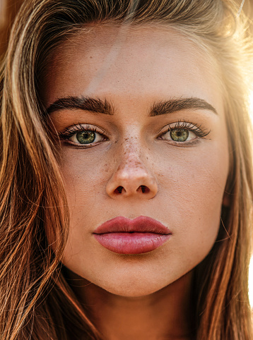 Beautiful young woman with natural freckles on face. Closeup portrait of an attractive girl with a delicate makeup. Skin care concept.