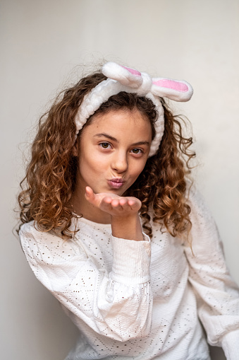 portrait of a girl with bunny ears on her head and blowing a kiss