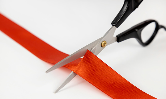 Close-up of scissors cutting a red satin ribbon