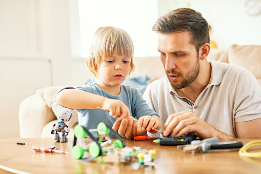 Portrait of a father and son, father teaching son to use tools and craftsmanship with creative toy at home